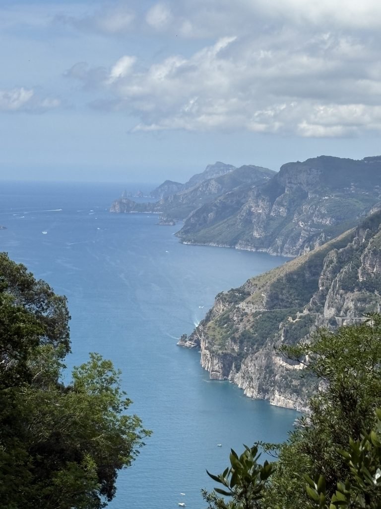 View along the mountainous Amalfi Coast from the Path of the Gods, with blue sea below.