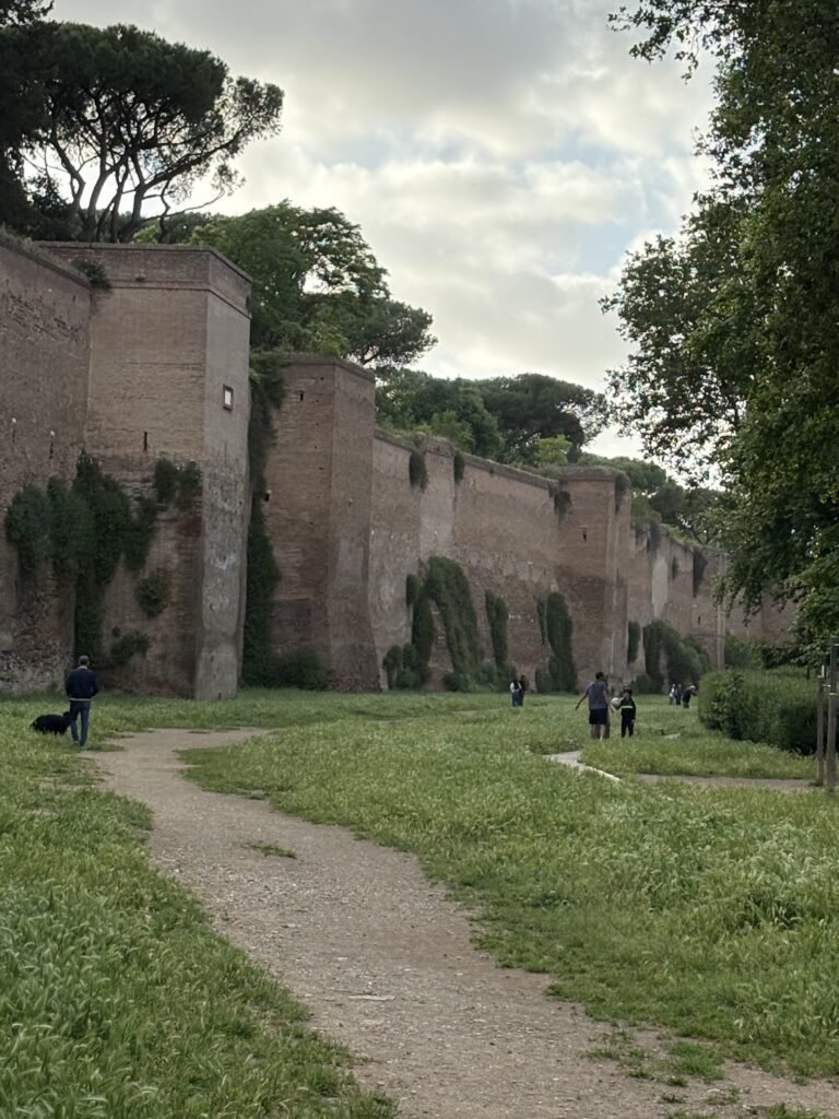 Long section of Rome's Aurelian Walls beside a grassy path.