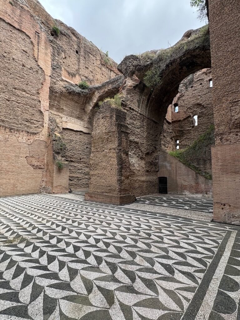 Black-and-white mosaic floor among the brick ruins of the Baths of Caracalla.