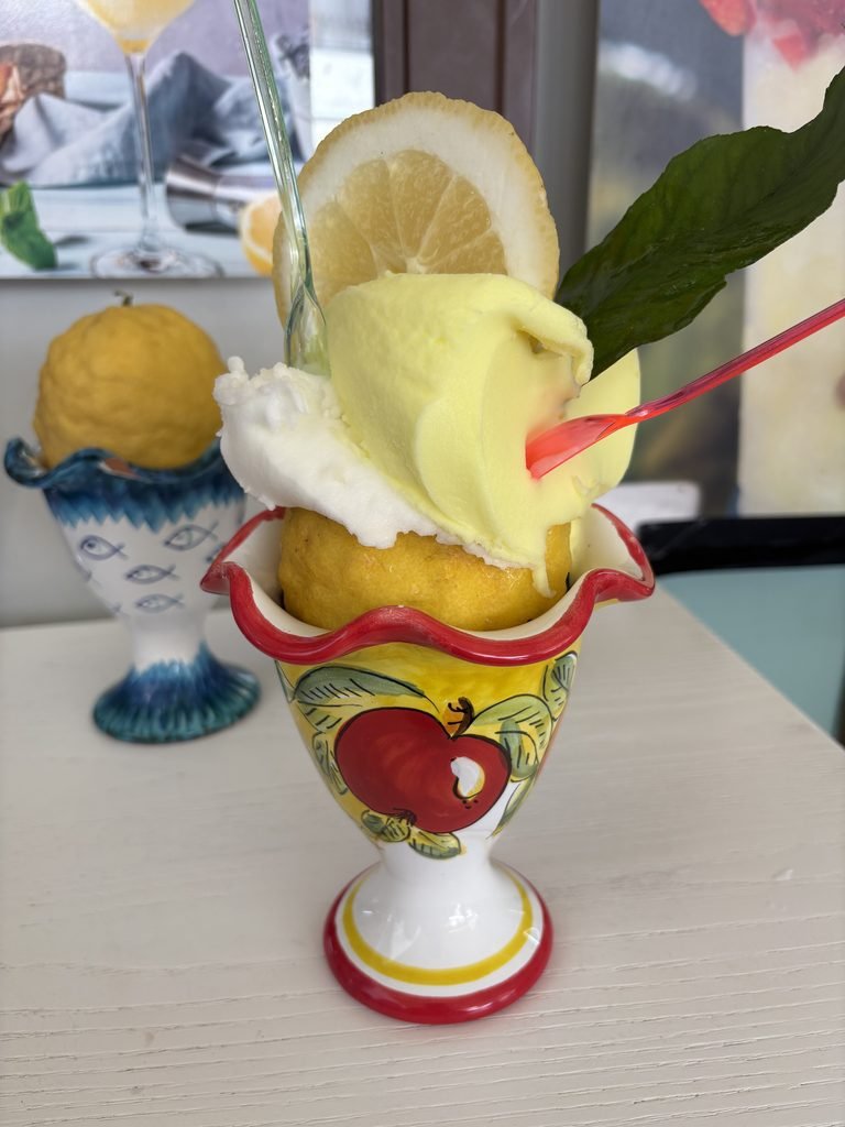 Lemon gelato served in a decorative cup with a lemon slice and leaf.