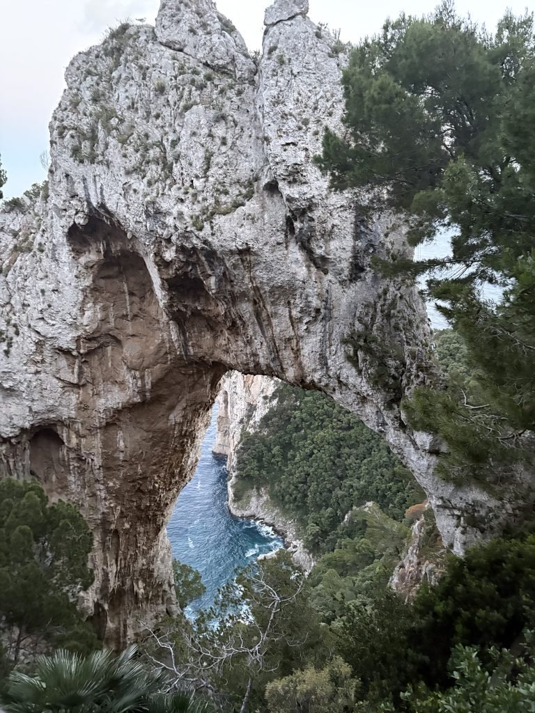 Natural Arch rock formation on Capri, framed by surrounding vegetation.
