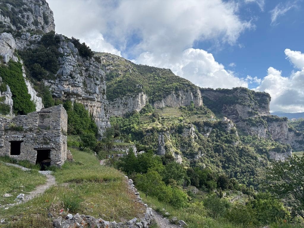 Path beside old stone buildings and terraced cliffs on the Path of the Gods.