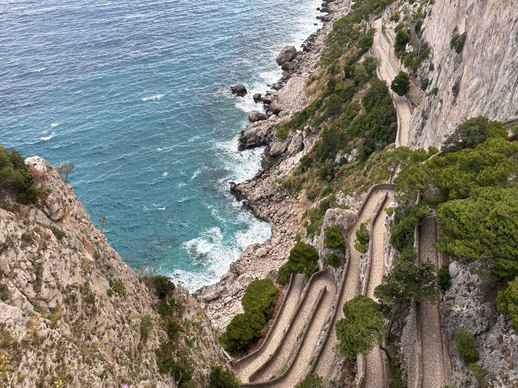 View down the winding Via Krupp path on Capri, with rocky cliffs and the sea below.